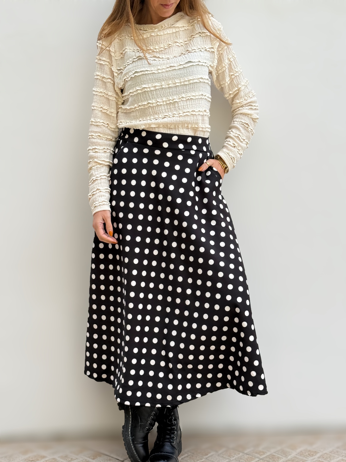 Saia midi preta com bolinhas brancas e blusa creme texturizada, botins pretos.