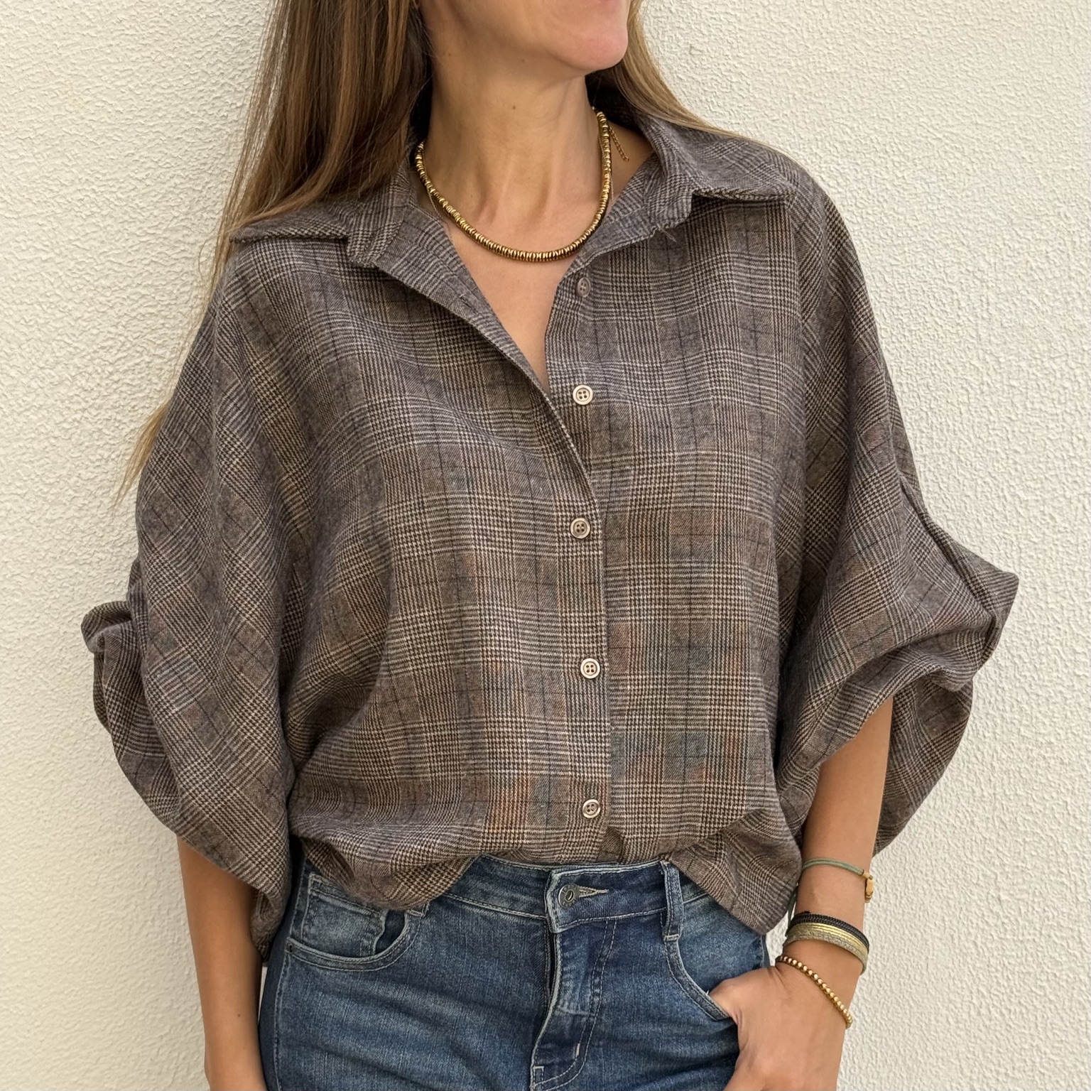 Blusa xadrez castanha cinzenta com botões e jeans azuis