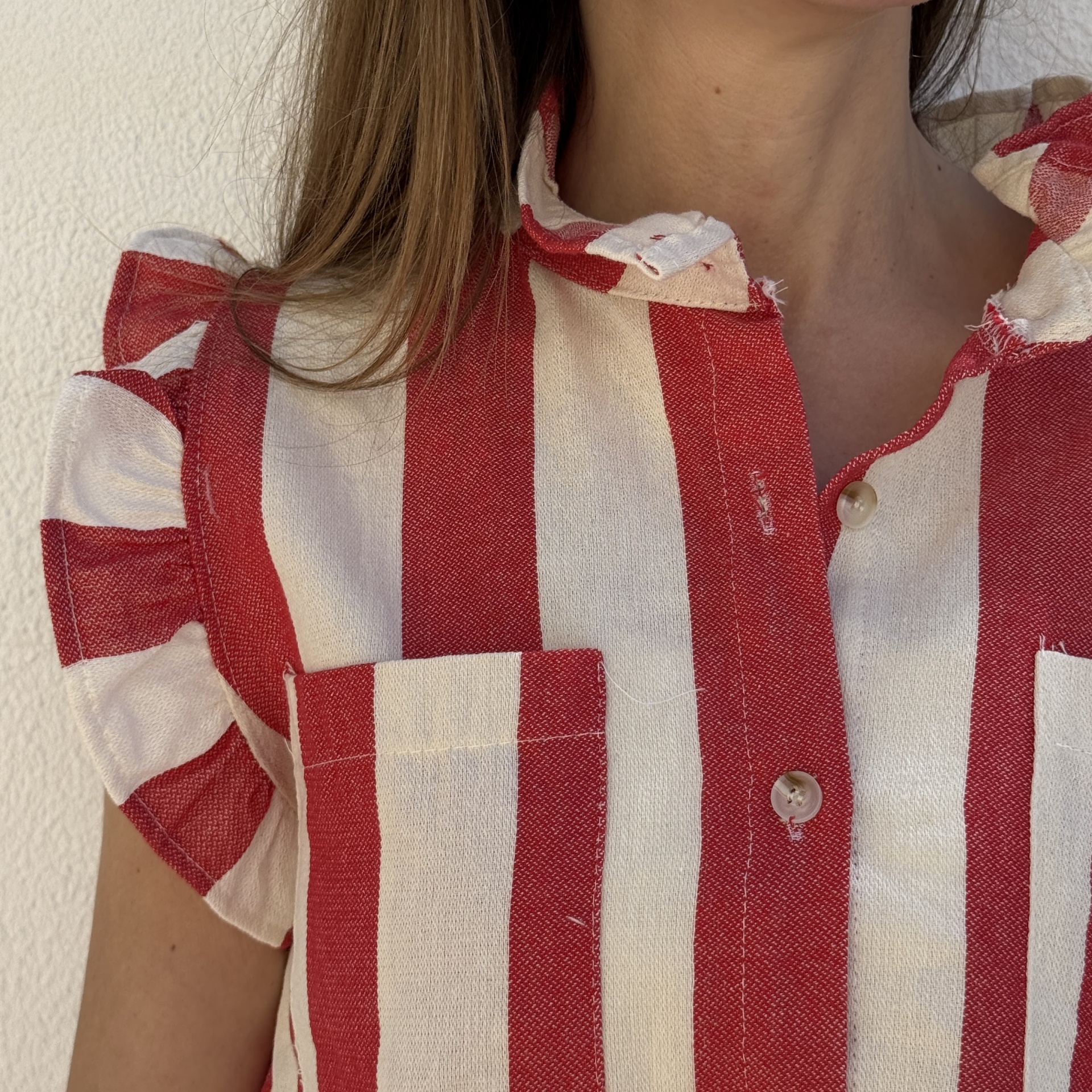 Camisa às riscas vermelhas e brancas com botões e gola desfiada