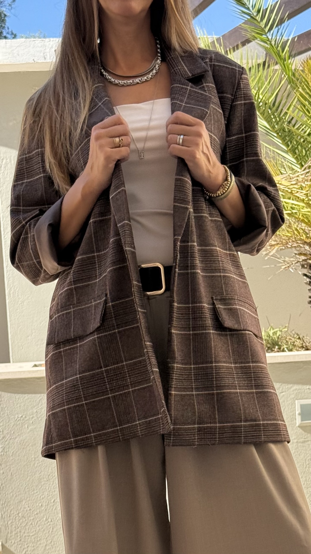 Blazer castanho escuro às riscas com bolsos, usado com blusa branca e calças largas bege.