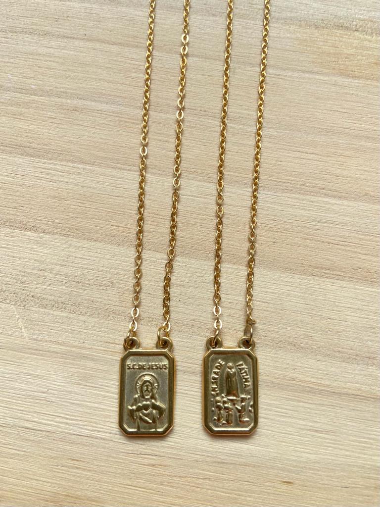 Colares dourados com pendentes retangulares gravados sobre madeira clara