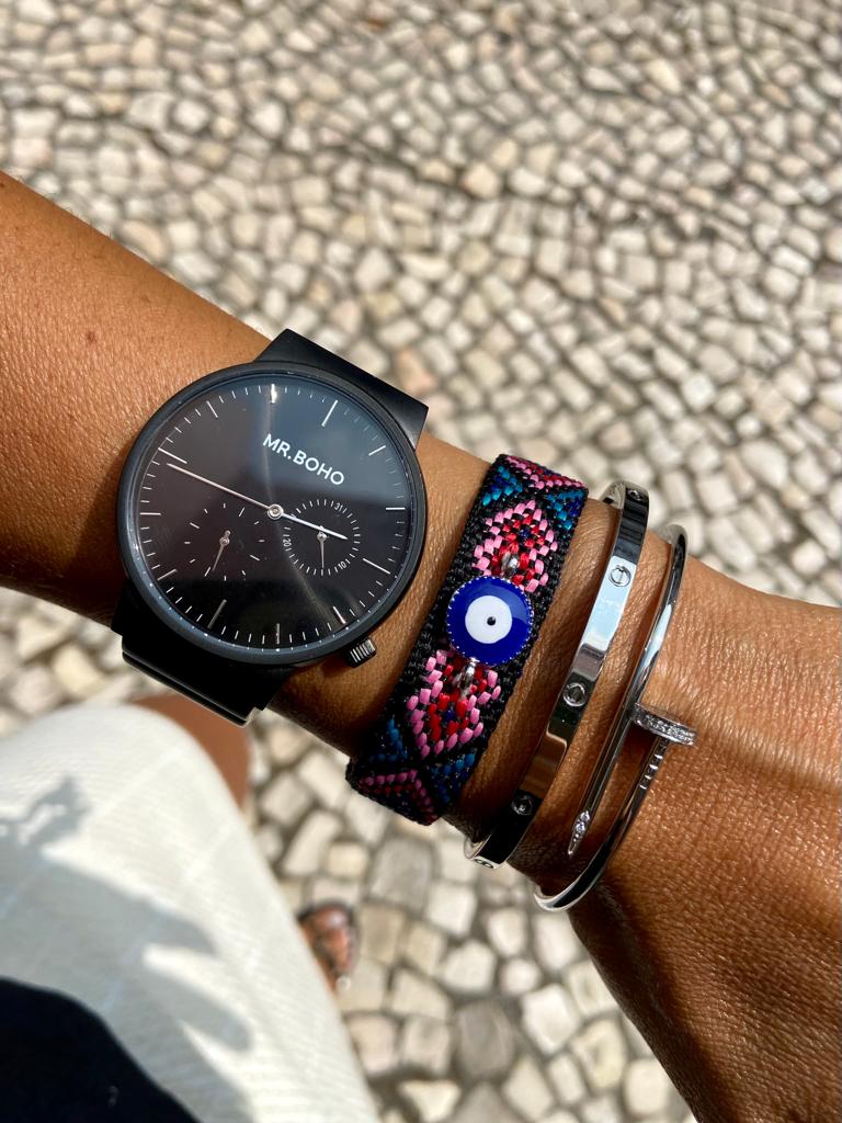 Relógio de pulso preto MR.BOHO com pulseiras coloridas e prateadas num pulso