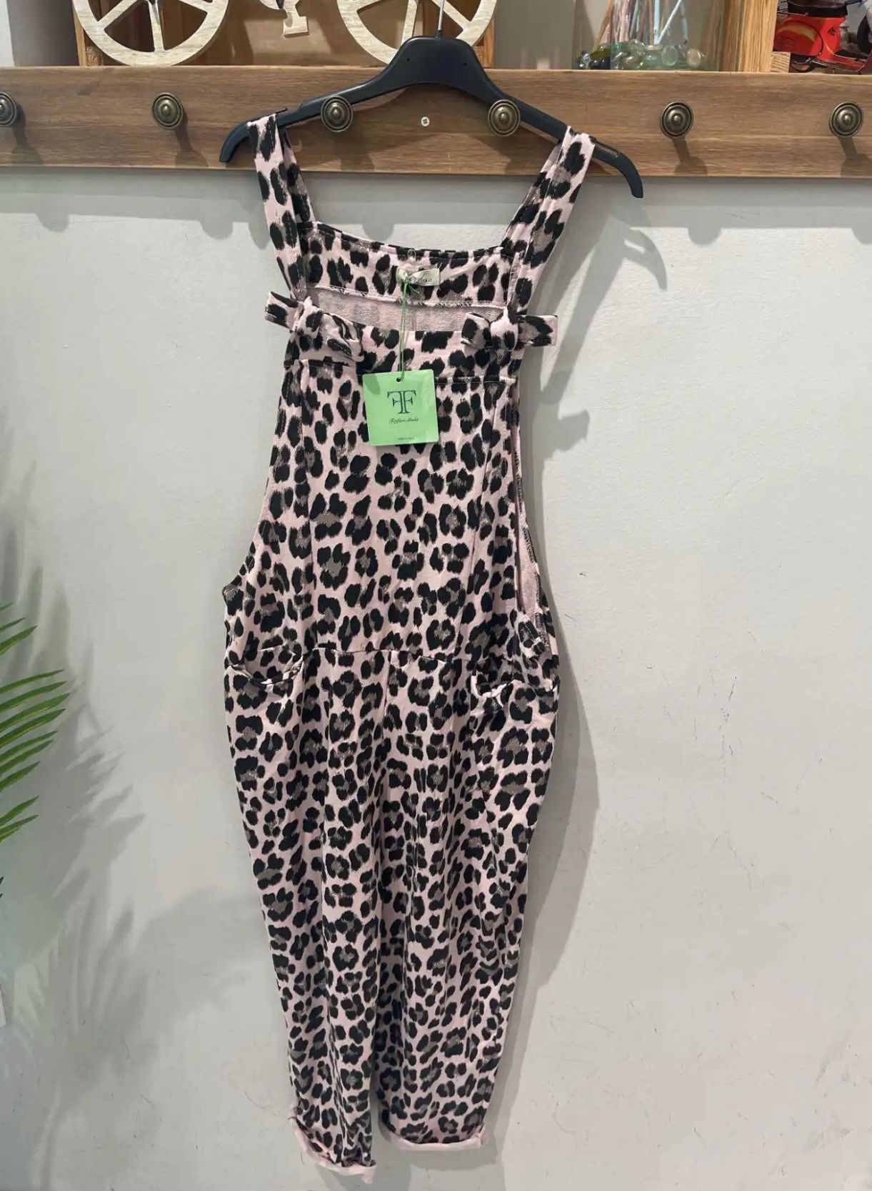 Macacão de tecido padrão manchas preto e bege pendurado numa parede branca