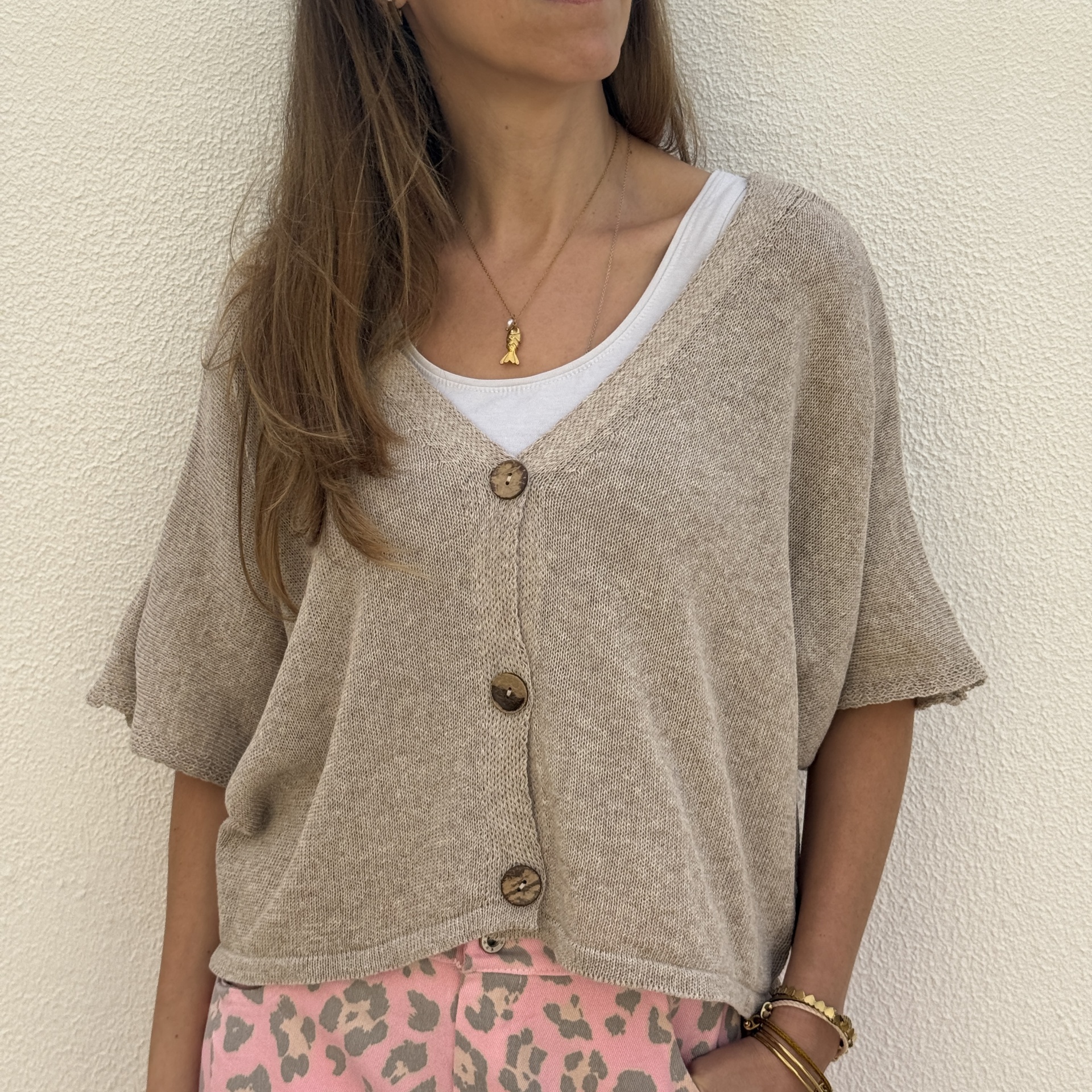 Mulher a usar cardigan bege com botões de madeira e calças rosa com padrão animal