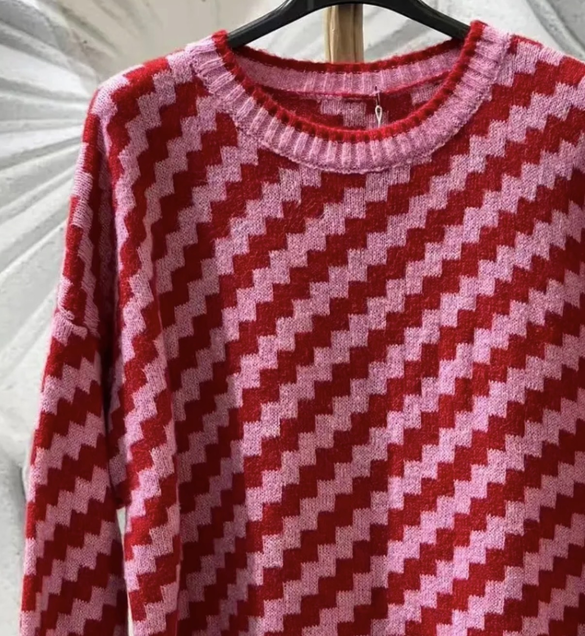 Camisola de malha vermelha e rosa com padrão em ziguezague num cabide preto