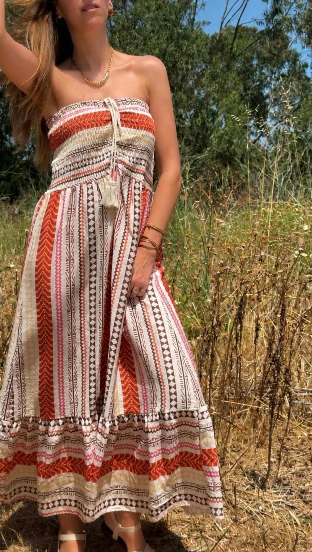 Vestido longo tomara que caia com padrão étnico em cores terra, usado ao ar livre