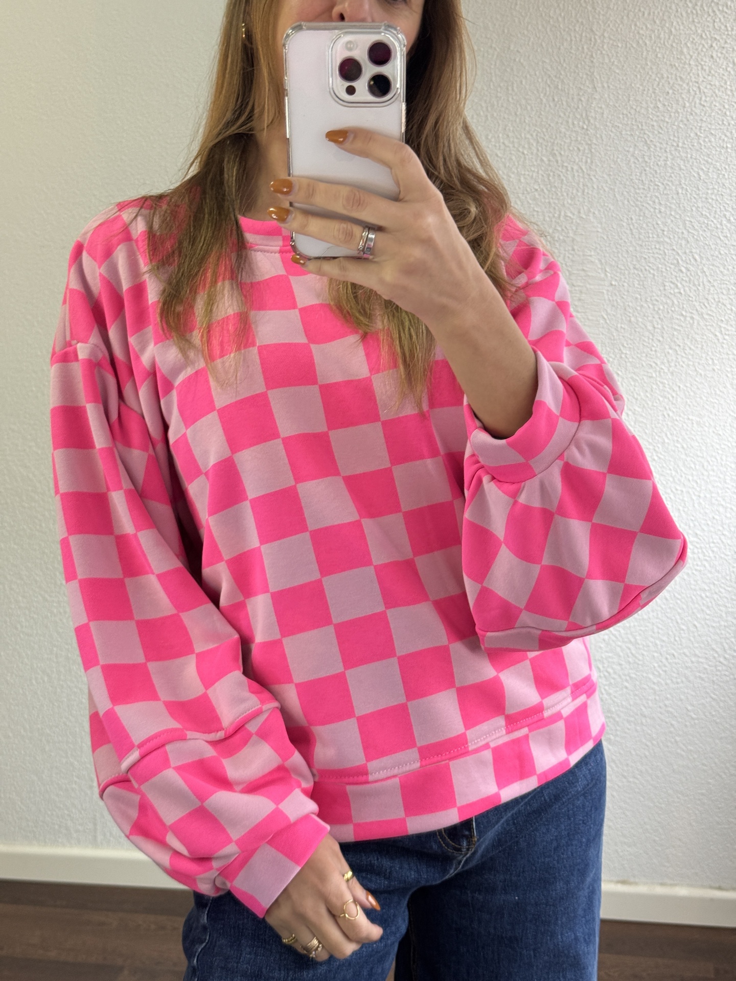 Sweatshirt quadriculada rosa e rosa claro com mangas largas e punhos ajustados, em interior com parede branca