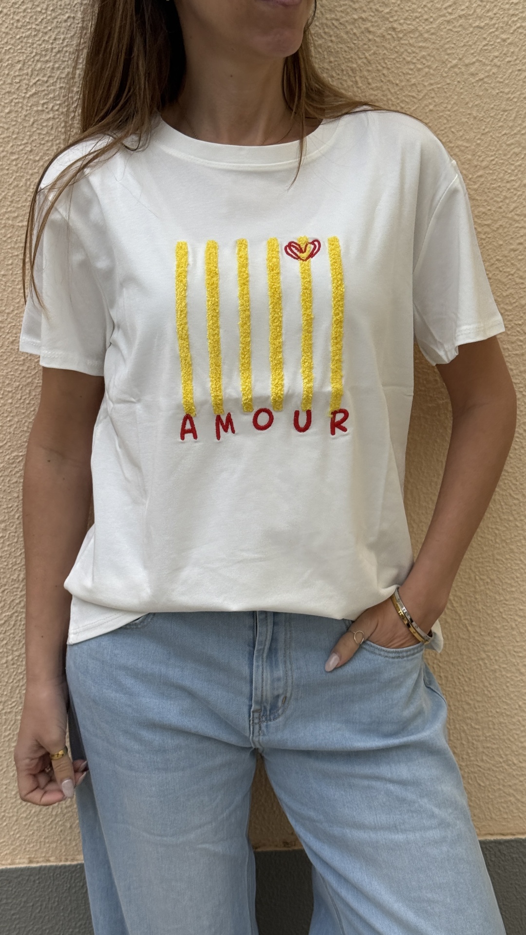 T-shirt branca com riscas amarelas e palavra AMOUR em vermelho.