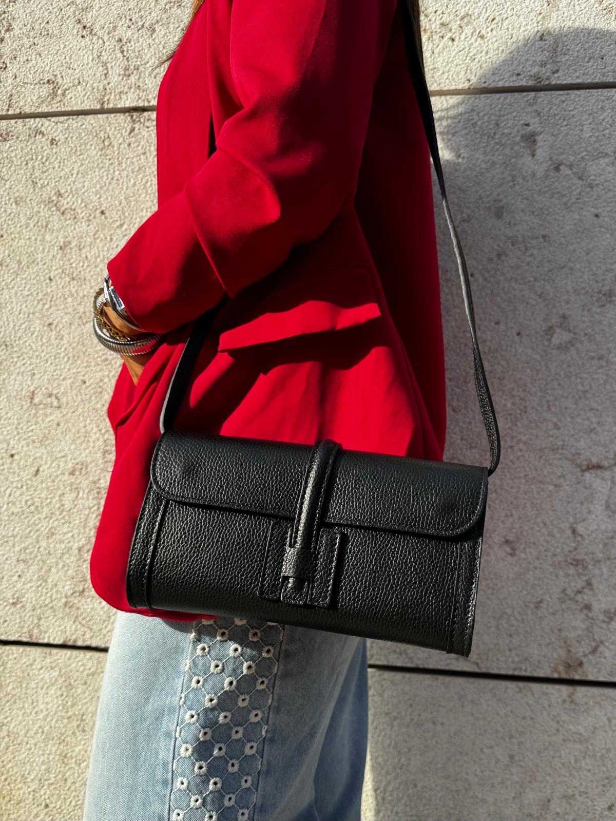 Mala preta de ombro em couro com fecho frontal e casaco vermelho
