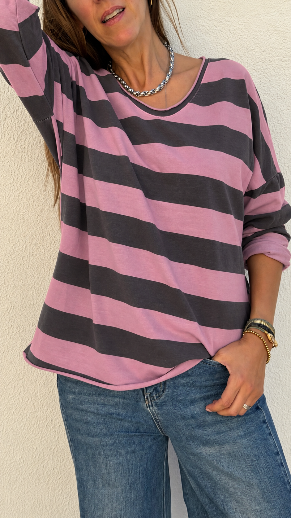 Camisola riscada cor-de-rosa e cinza com calças de ganga azuis e acessórios em prata e ouro