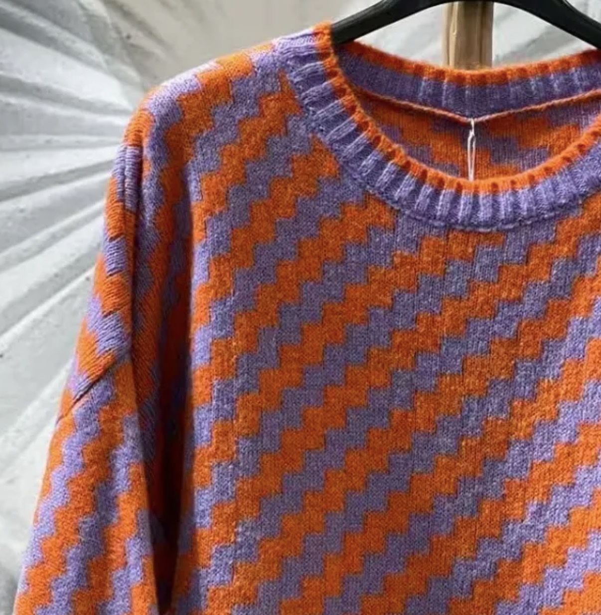 Camisola de malha laranja e roxa com padrão ziguezague e gola redonda.