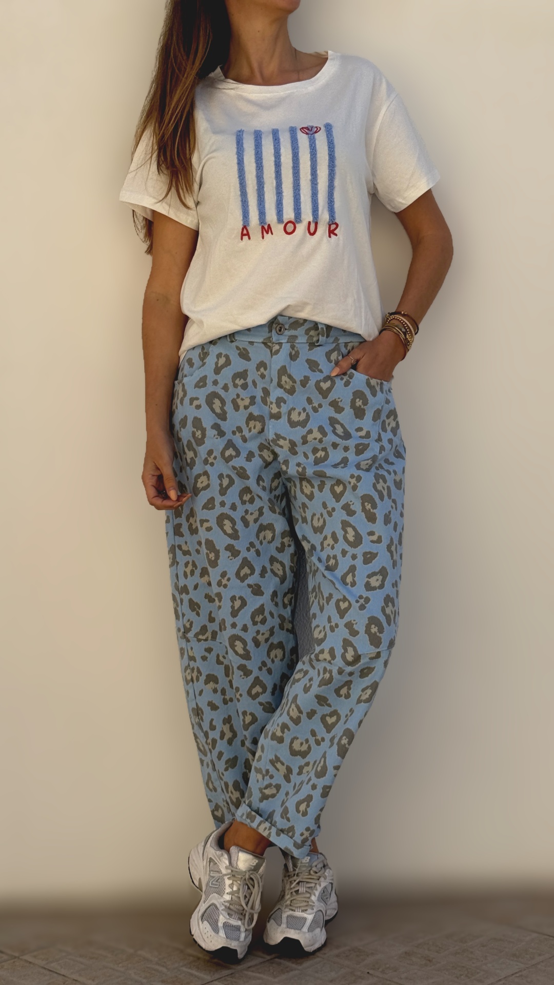 T-shirt branca com estampado AMOUR e calças azul claro com padrão animal print cinza.