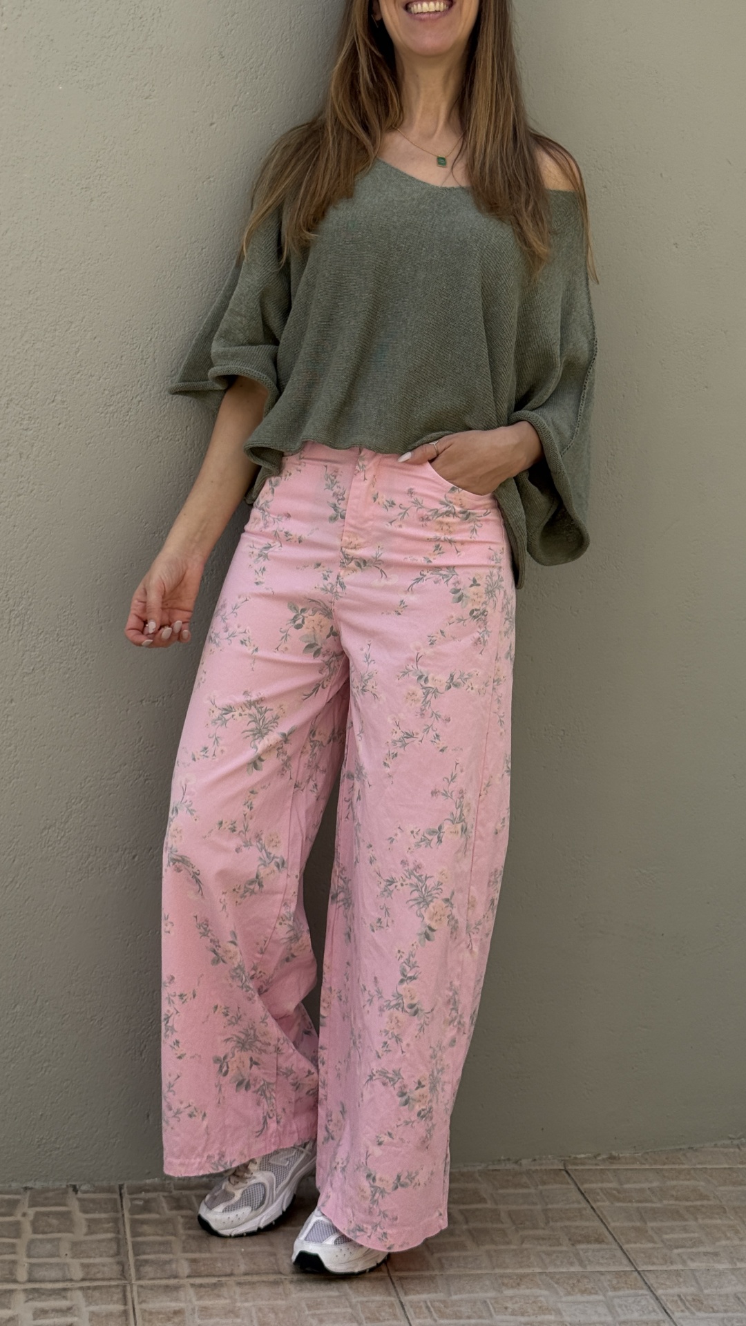 Calças largas rosa com padrão floral cinzento, camisola verde oversize e ténis brancos