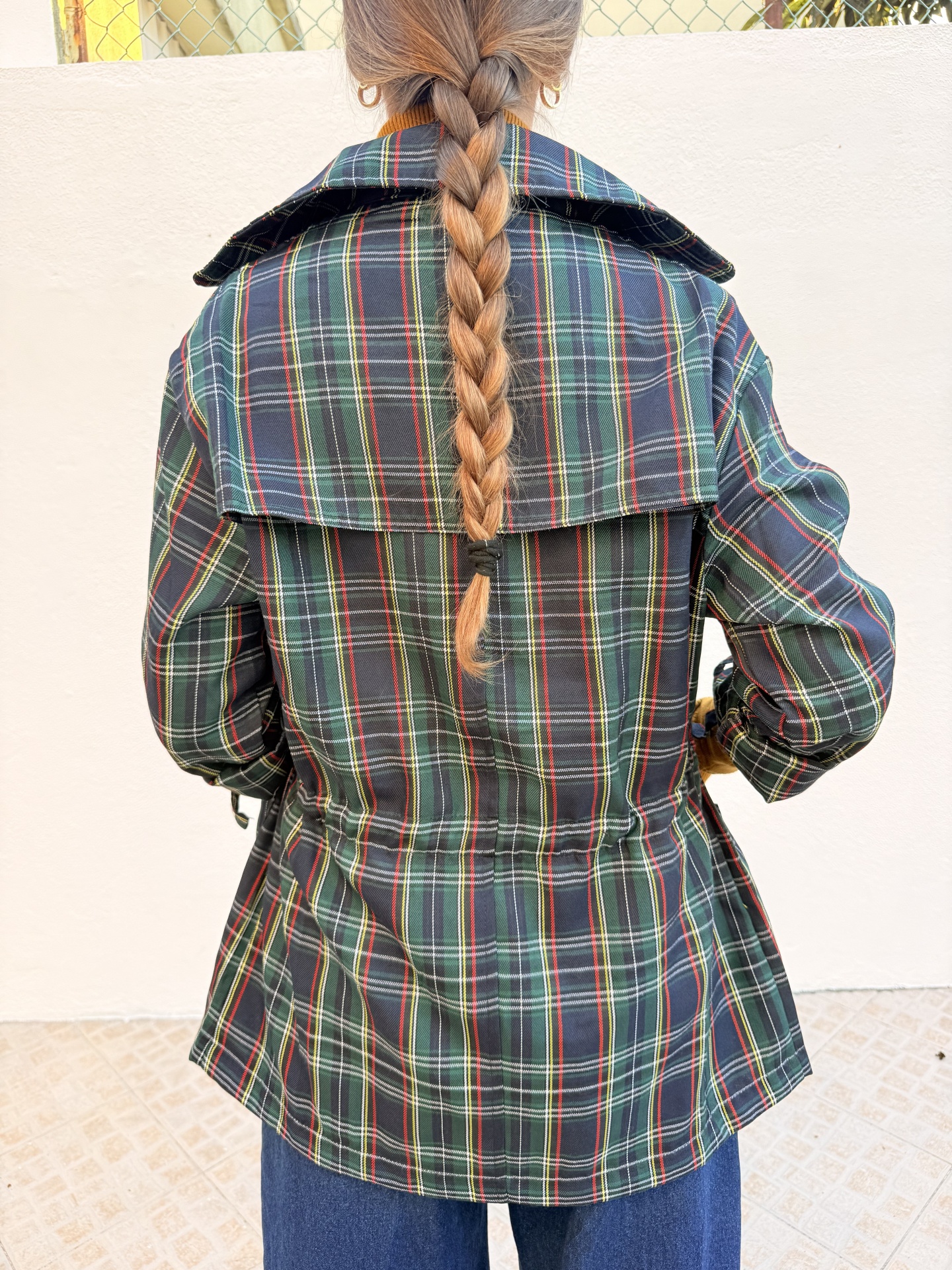 Casaco tipo parka xadrez verde, amarelo, vermelho e branco visto das costas.