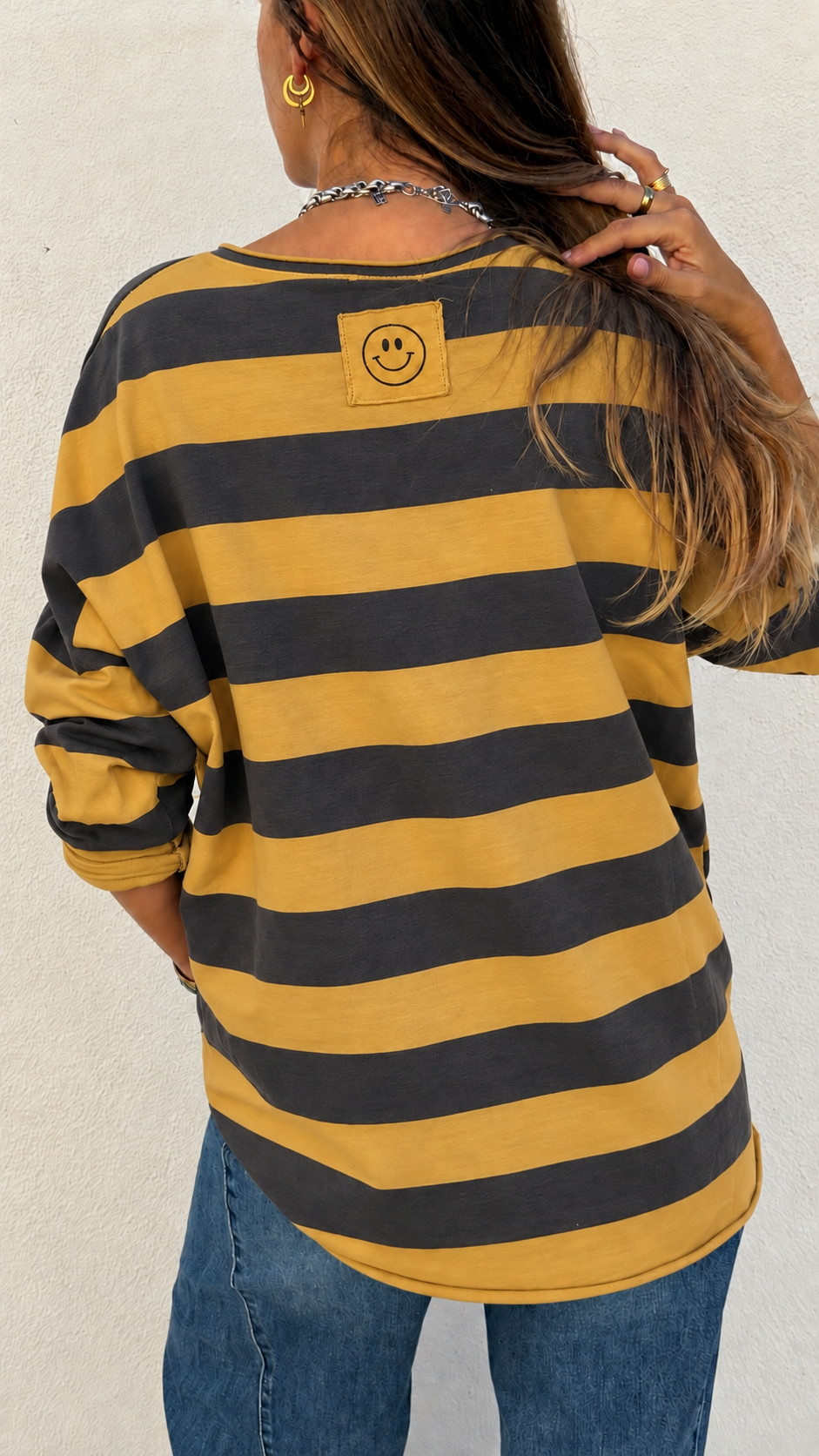 T-shirt riscada amarela e preta com sorriso nas costas vista de trás