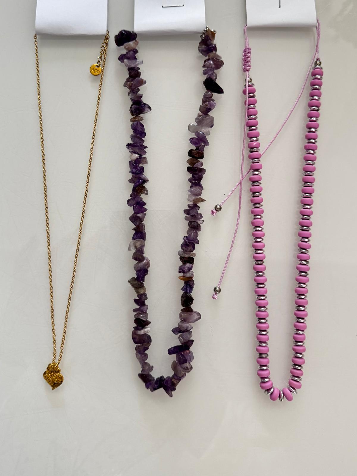 Quatro colares diferentes pendurados em fundo branco.