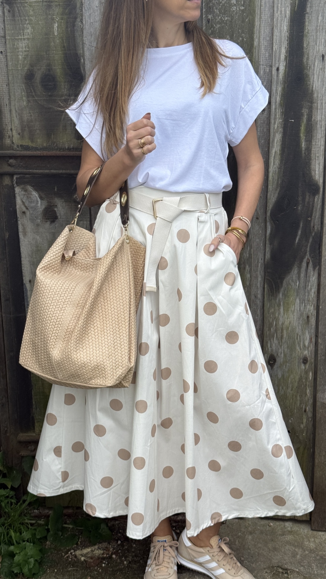 Saia branca com bolinhas castanhas, t-shirt branca, ténis bege e mala bege trançada