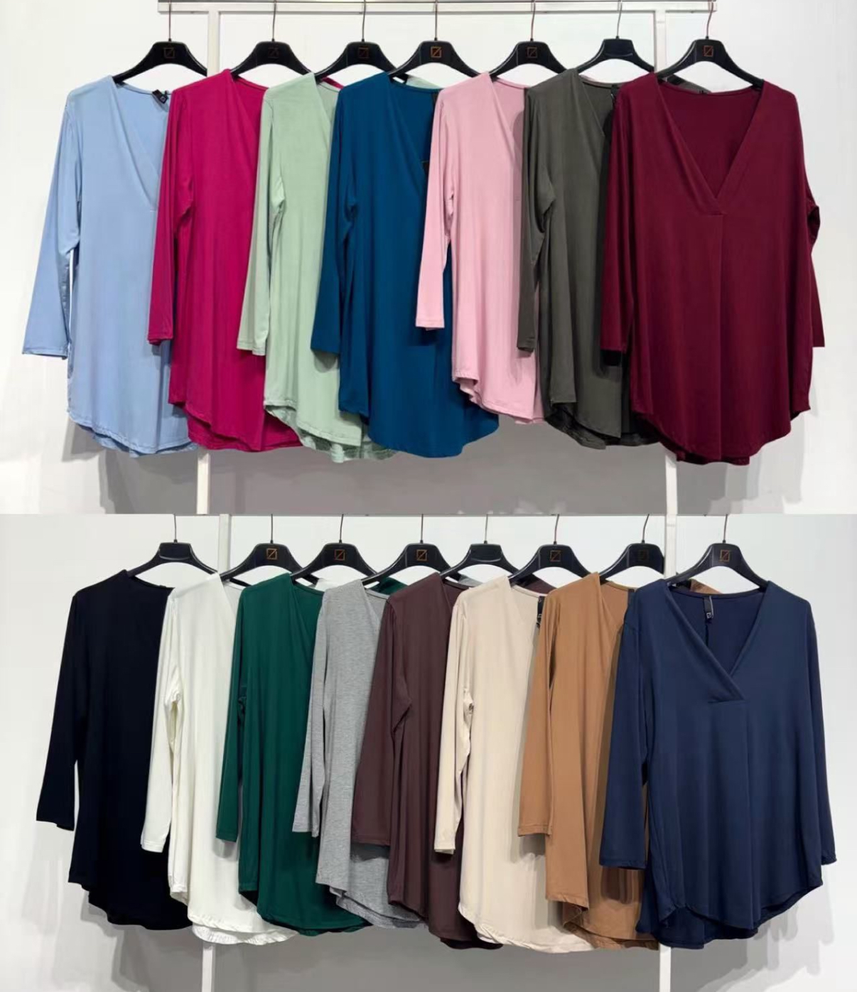 Blusas de manga comprida coloridas penduradas em cabides pretos em duas fileiras.