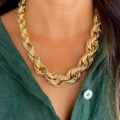 Colar dourado texturizado em pescoço com camisa verde