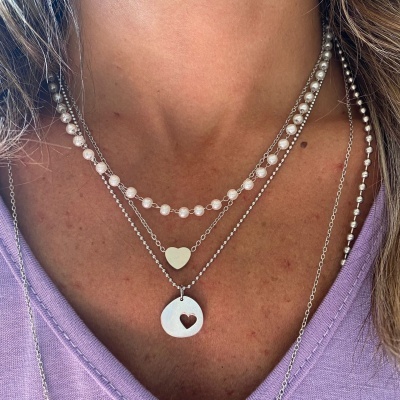 colar triplo com pendentes em forma de coração e pérolas sobre camisa lilás