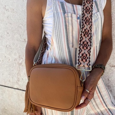 Bolsa castanha em pele com alça larga padrão geométrico usado com macacão riscas