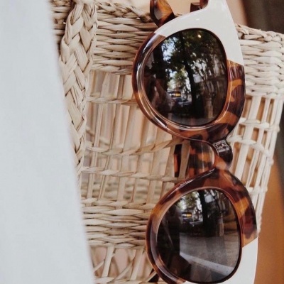 Óculos de sol bicolores pendurados numa cadeira de vime