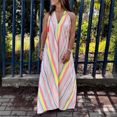 Vestido longo listrado colorido usado por mulher em zona exterior com grades azuis ao fundo
