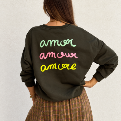 Mulher de costas usando sweatshirt preta com palavras coloridas e saia xadrez branca