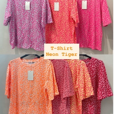 Sete t-shirts com padrão animal print em várias cores neon penduradas em cabides pretos