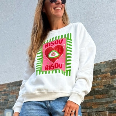Mulher a usar sweatshirt branca com estampa colorida e calções de ganga azuis em exterior