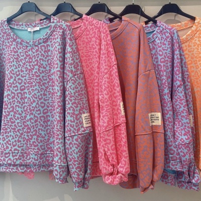 Cinco sweatshirts coloridas com padrão de leopardo penduradas em cabides pretos