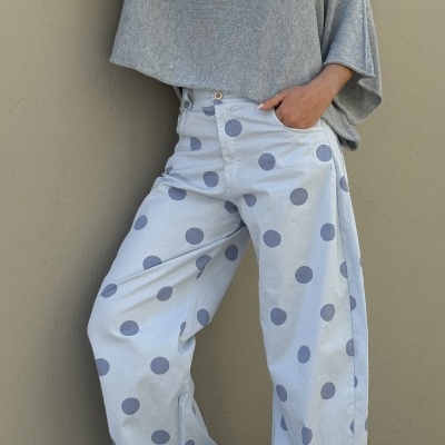 Calças largas azuis claras com bolinhas azuis escuras, top cinzento de malha e sapatilhas brancas