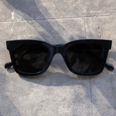 Óculos de sol pretos com lentes escuras sobre superfície de cimento