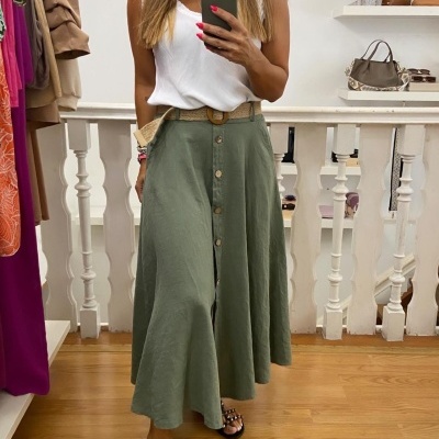 Saia midi verde clara com botões e cinto, camisa branca sem mangas e sandálias pretas em ambiente interior