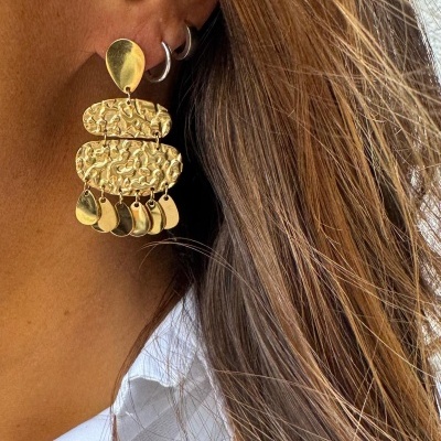 Brinco de ouro com diferentes texturas usado em orelha feminina