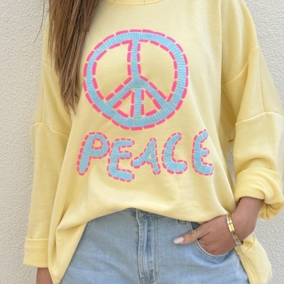 Sweatshirt amarela com estampa símbolo da paz e palavra PEACE em azul claro com contorno rosa.