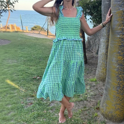 Vestido curto xadrez azul e verde com folhos num jardim com vista para o mar
