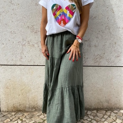 Mulher com t-shirt branca e saia longa verde