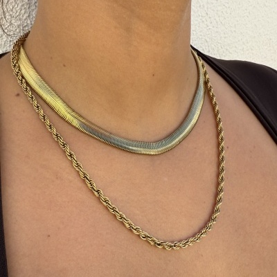 Colares dourado e prateado e brinco em argola dourada no pescoço e orelha de mulher