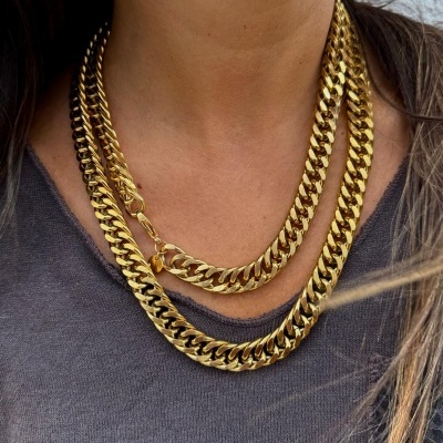 Colar de corrente grossa dourada em duas voltas numa pessoa com camisola cinza escura