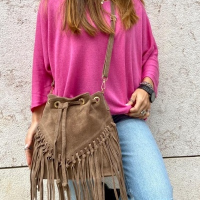 Saco castanho de camurça com franjas, mulher com camisola rosa e calças de ganga rasgadas