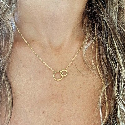 Colar dourado com dois anéis entrelaçados no pescoço