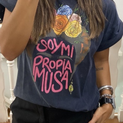 T-shirt preta com flores coloridas e texto em rosa, usada com saia preta.