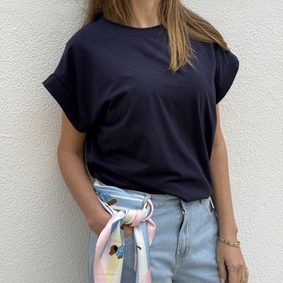 Mulher vestindo t-shirt preta e calças de ganga claras com lenço colorido amarrado no cinto