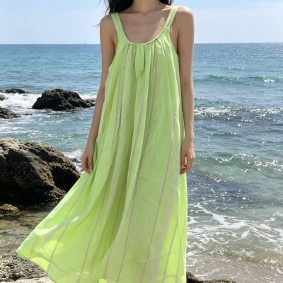 Vestido leve verde claro com padrões verticais em tela transparente junto ao mar e rochas