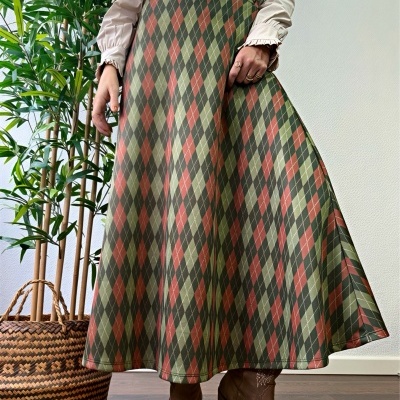 Saia comprida com padrão de losangos em verde, castanho e terracota com botins castanhos em ambiente interior