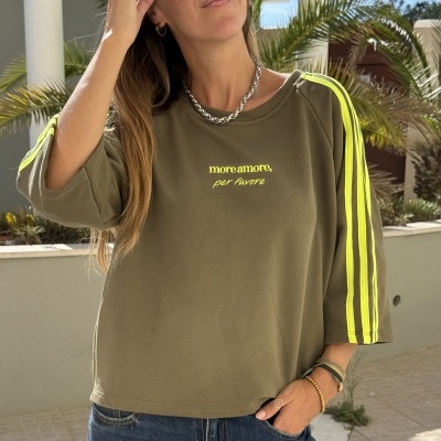 Sweatshirt verde com listas amarelas fluorescentes nas mangas e texto amarelo no peito e calças de ganga azuis