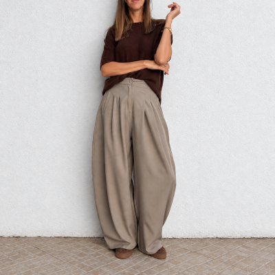 Calças largas bege com pregas, camisola castanha de malha, pulseira dourada e sapatos castanhos