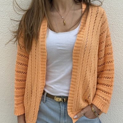 Cardigan de malha laranja perfurada com t-shirt branca e calças de ganga