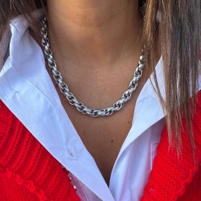 Colar de metal prateado com elos grossos, camisa branca e suéter vermelho tricotado.